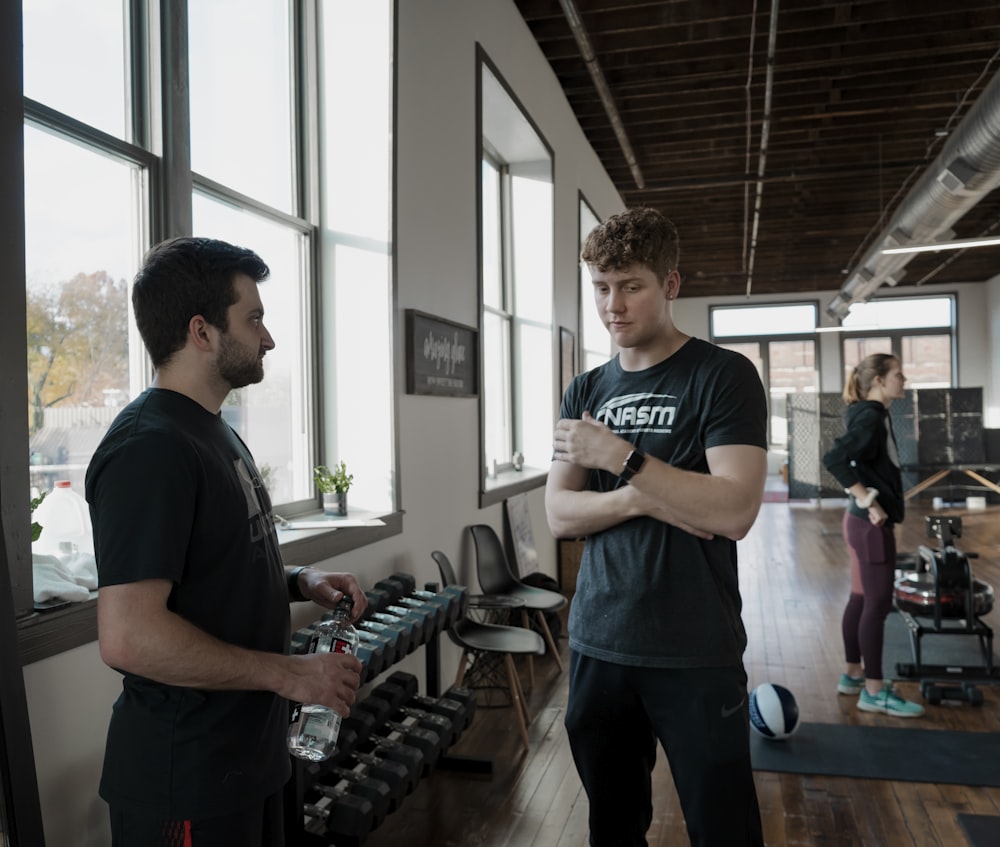 a man standing next to another man in a gym