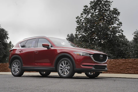 a red mazda cx - 5 parked on the side of the road