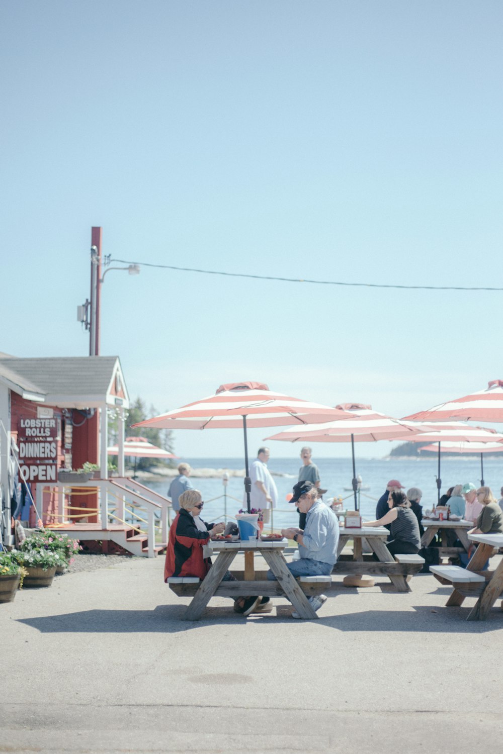 a group of people sitting at picnic tables under umbrellas