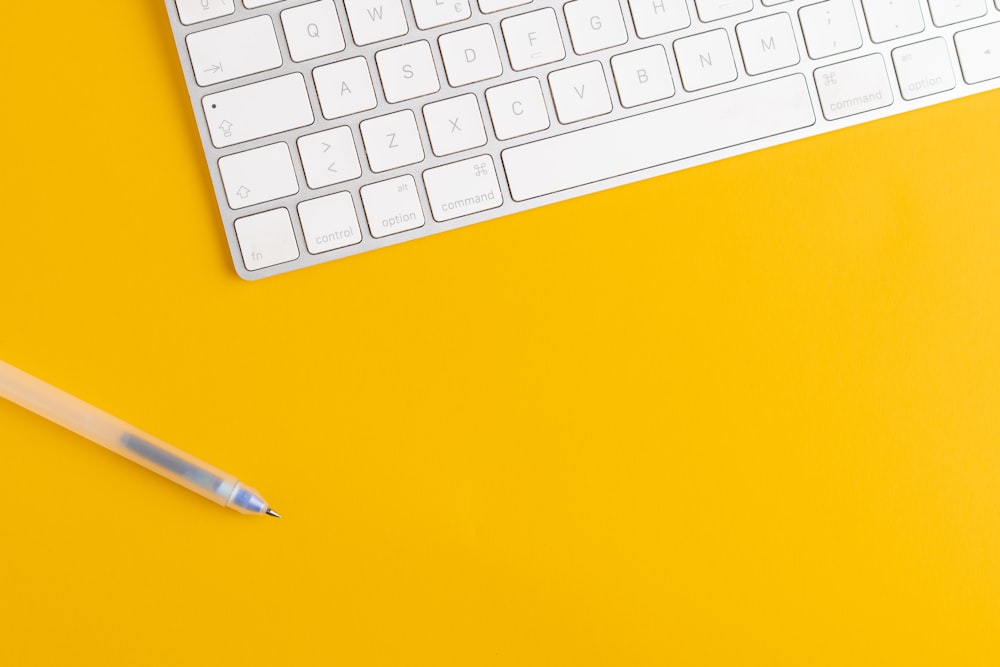 a keyboard and a pencil on a yellow background