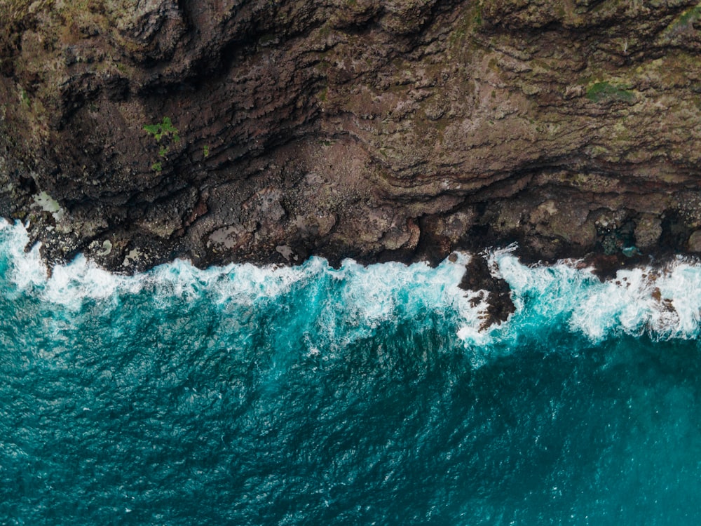 an aerial view of the ocean with a cliff in the background