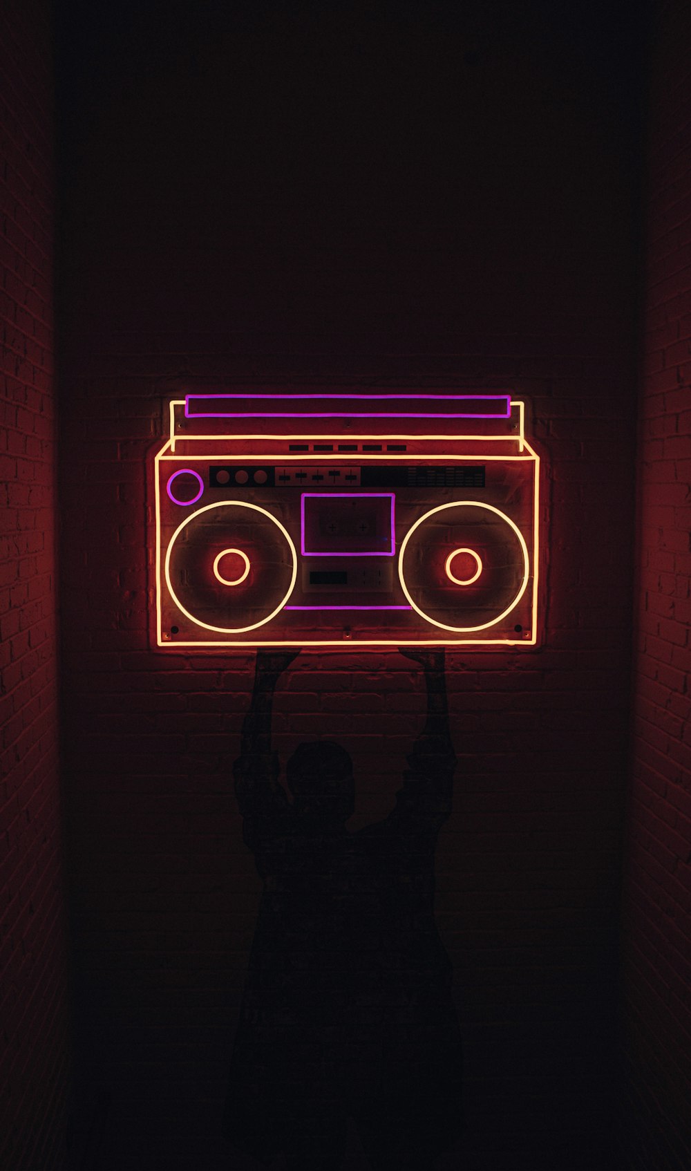 a person holding up a neon sign with a boombox on it