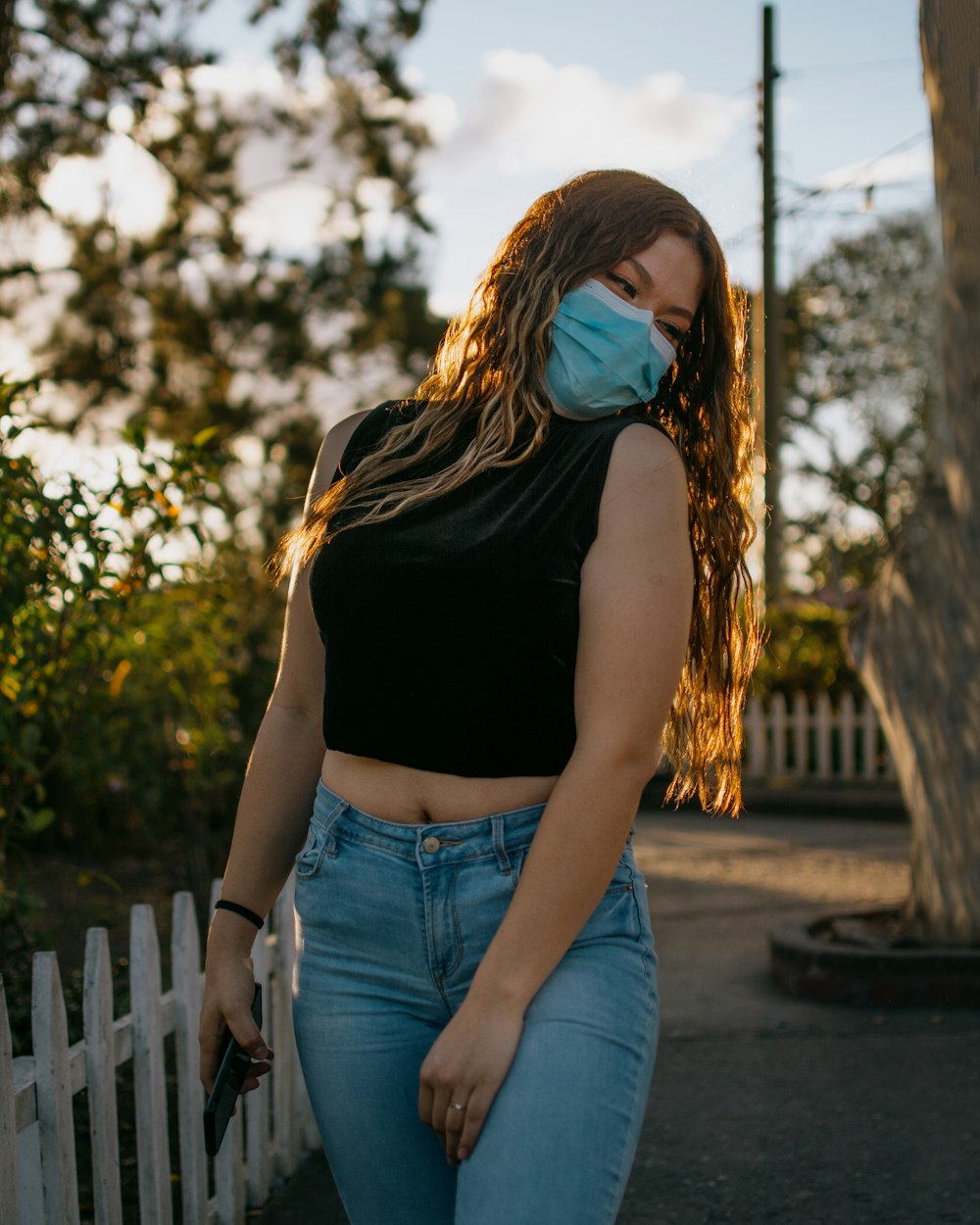 a woman wearing a face mask and jeans
