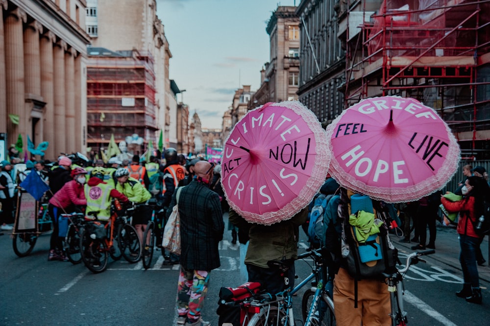 a group of people walking down a street with pink umbrellas