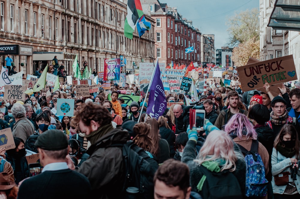 a crowd of people walking down a street holding signs