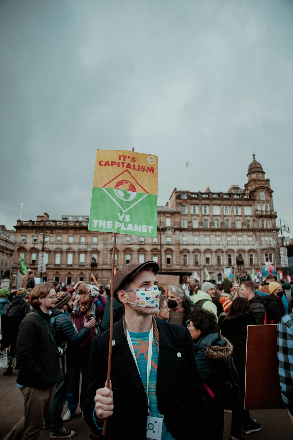 a man holding a green sign in front of a crowd of people