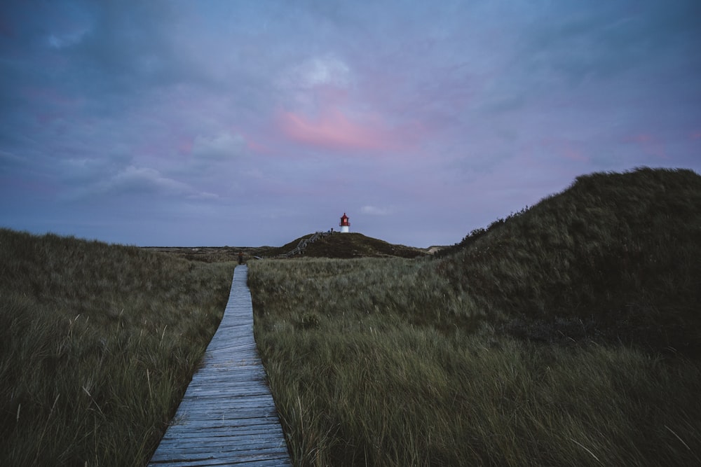 a wooden path leading to a lighthouse on a hill