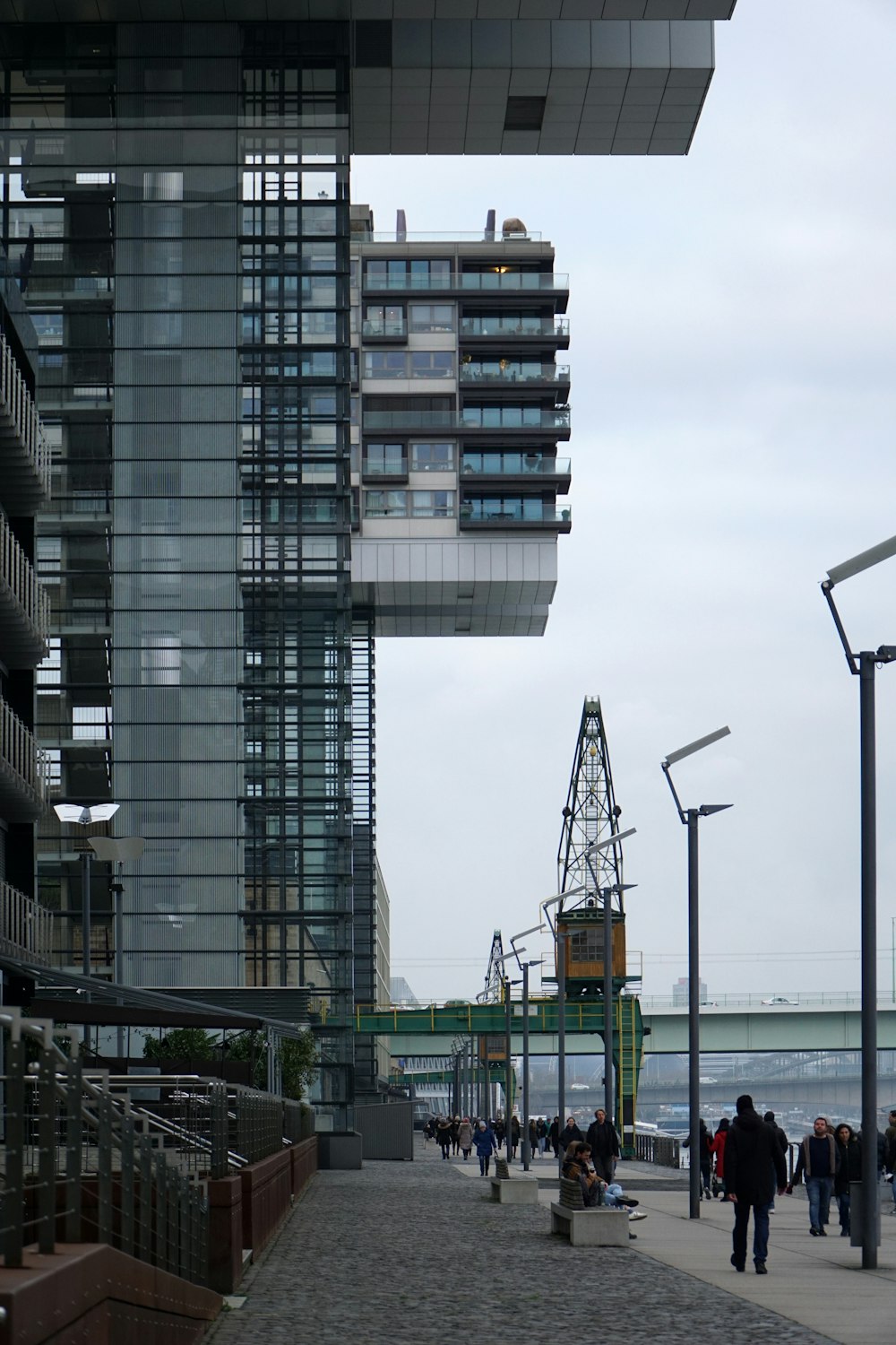 a group of people walking down a sidewalk next to a tall building