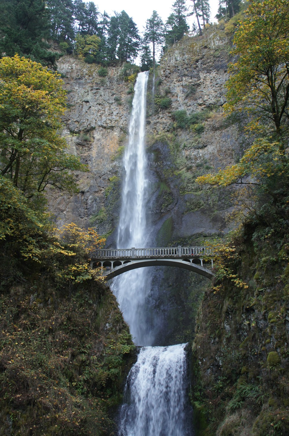 a large waterfall with a bridge over it