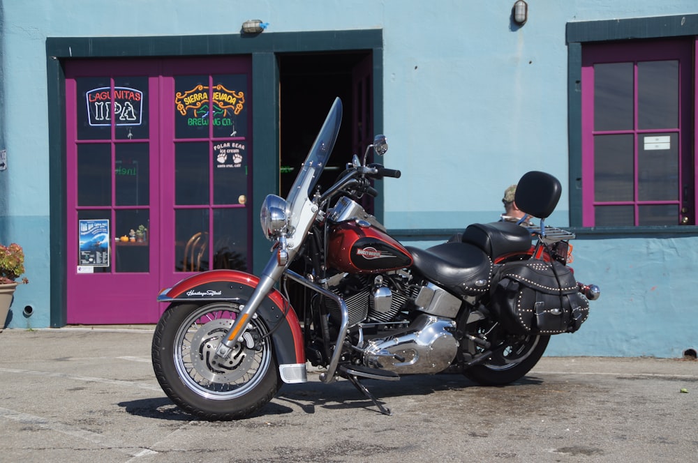 a red and black motorcycle parked in front of a building