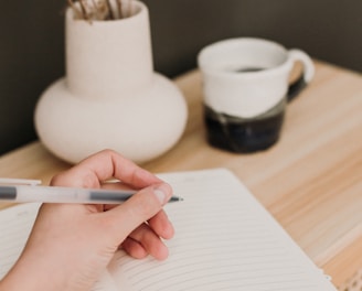 a person writing on a notebook with a pen