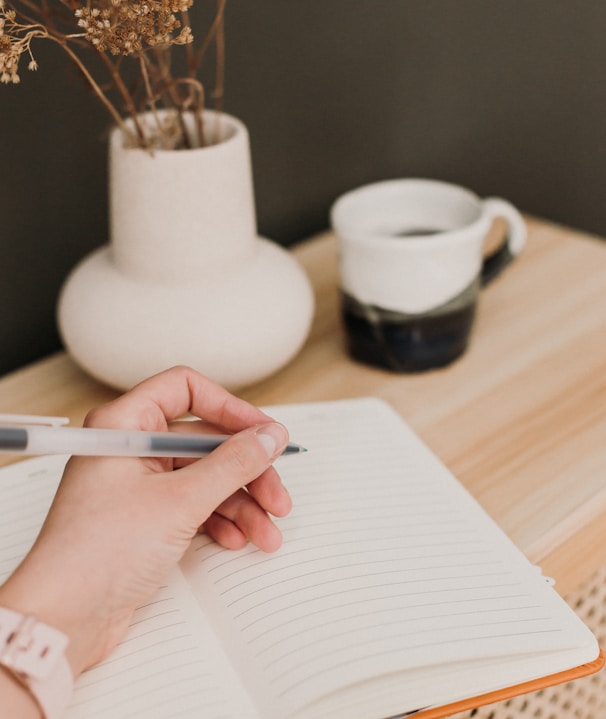 a person writing on a notebook with a pen