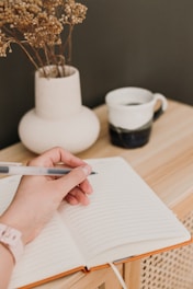 a person writing on a notebook with a pen