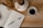A notebook with lined pages labeled 'Reflection' lies open on a wooden table, with a pen resting on its pages. Nearby, there is a white ceramic mug filled with black coffee. Some dried flowers in a white vase are also present on the table.