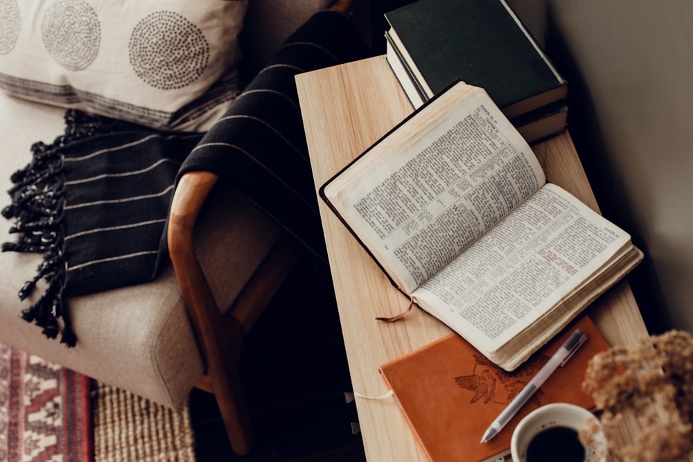 uma mesa com um livro, uma xícara de café e um ursinho de pelúcia