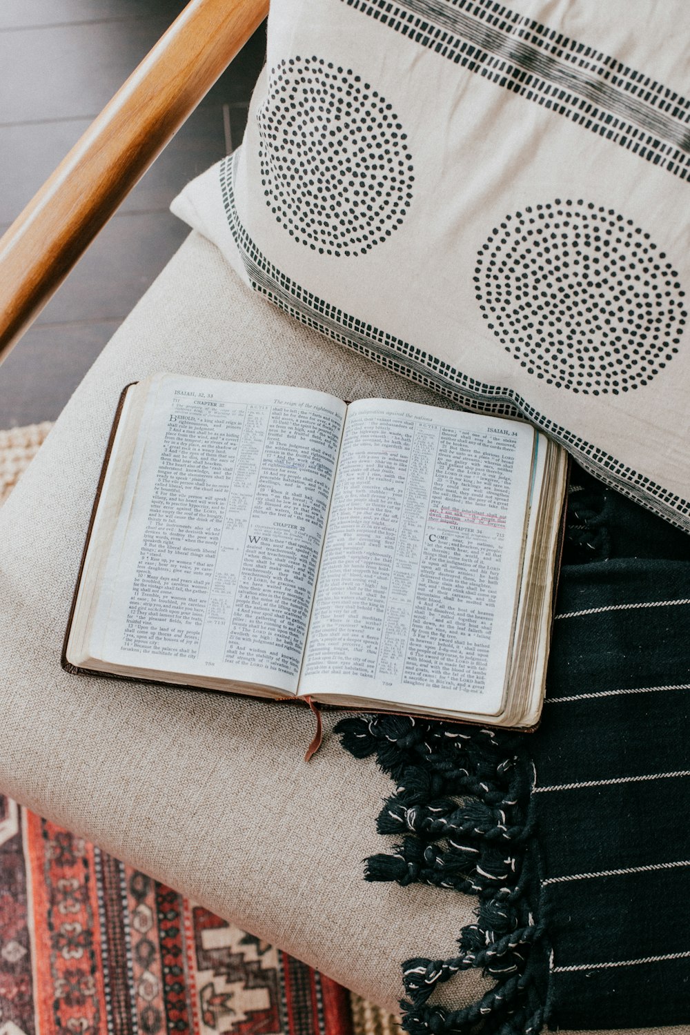 an open book sitting on top of a chair next to a pillow