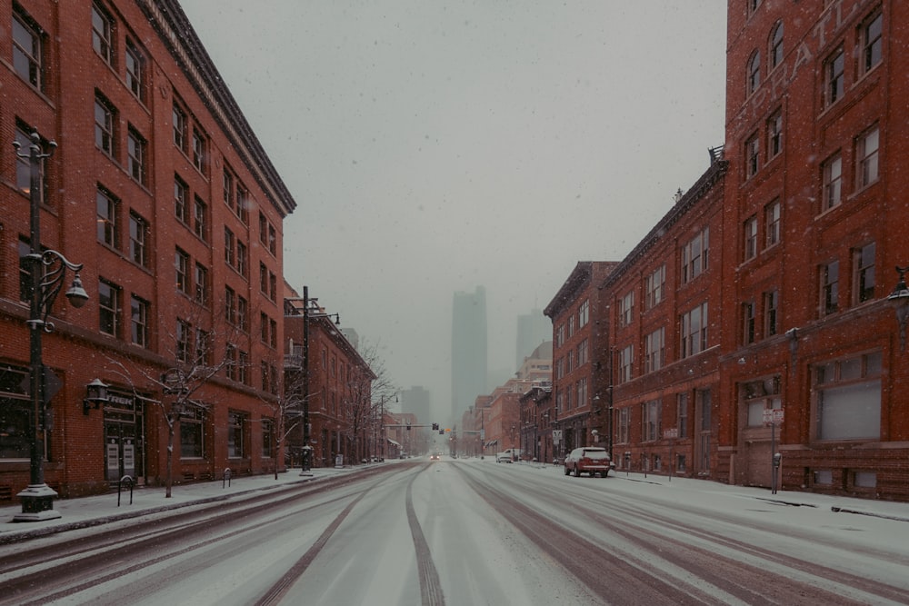 a snowy street with buildings and cars on it