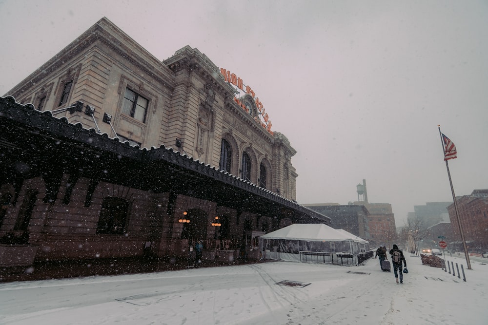 people walking in the snow in front of a building