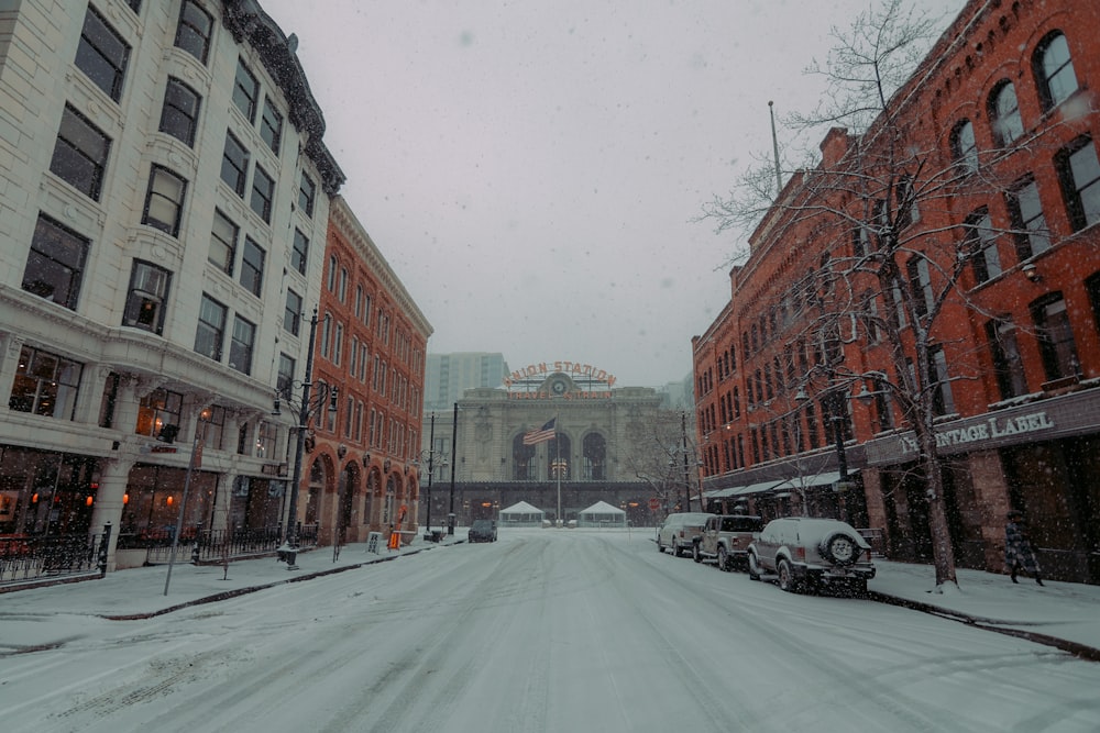 a snow covered street with cars parked on both sides