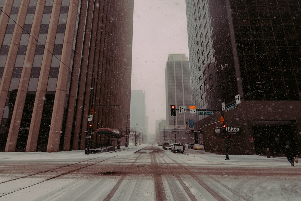 a snowy city street with tall buildings and traffic lights