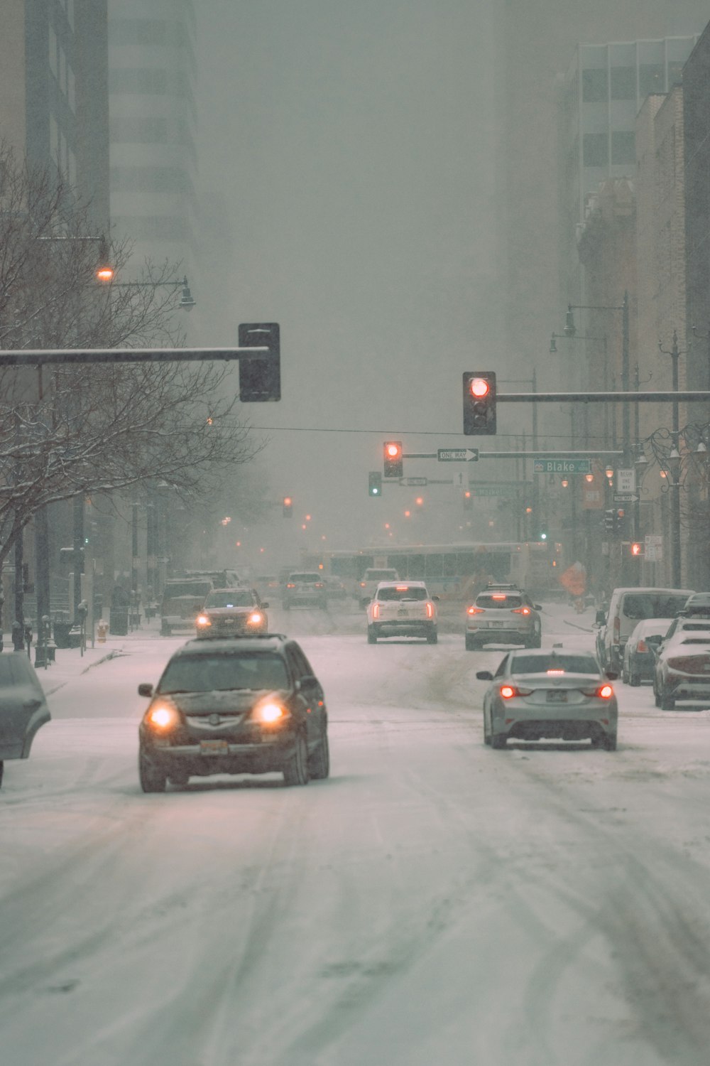 a city street filled with lots of traffic covered in snow