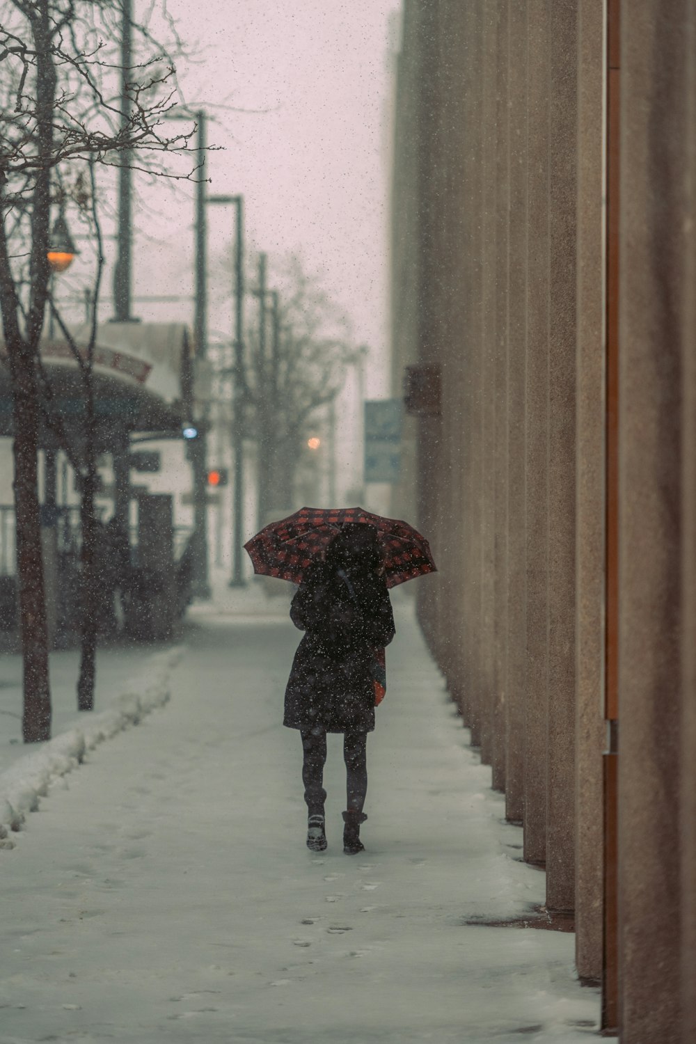 a person walking down a snowy sidewalk with an umbrella
