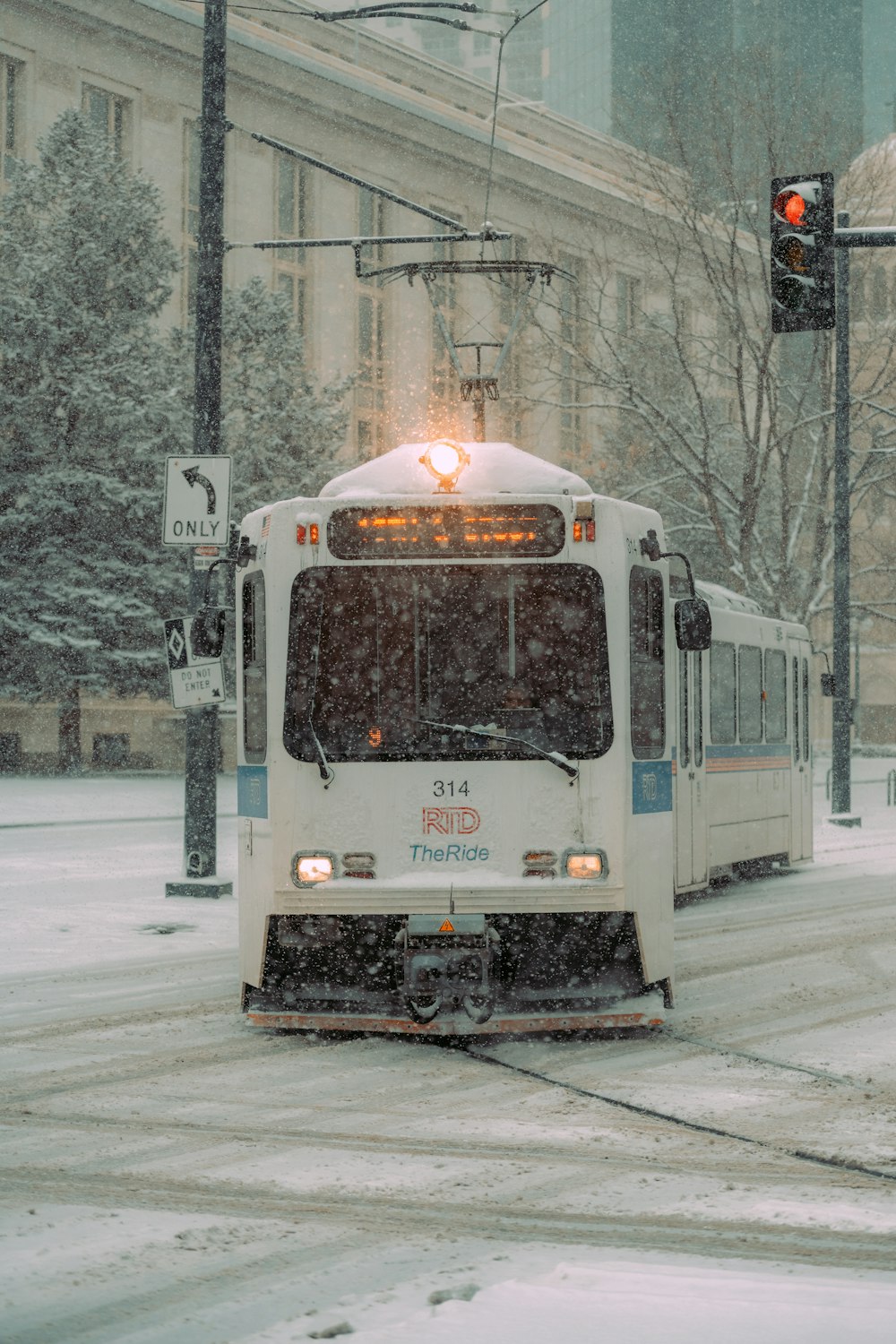 a bus driving down a snowy street next to a traffic light