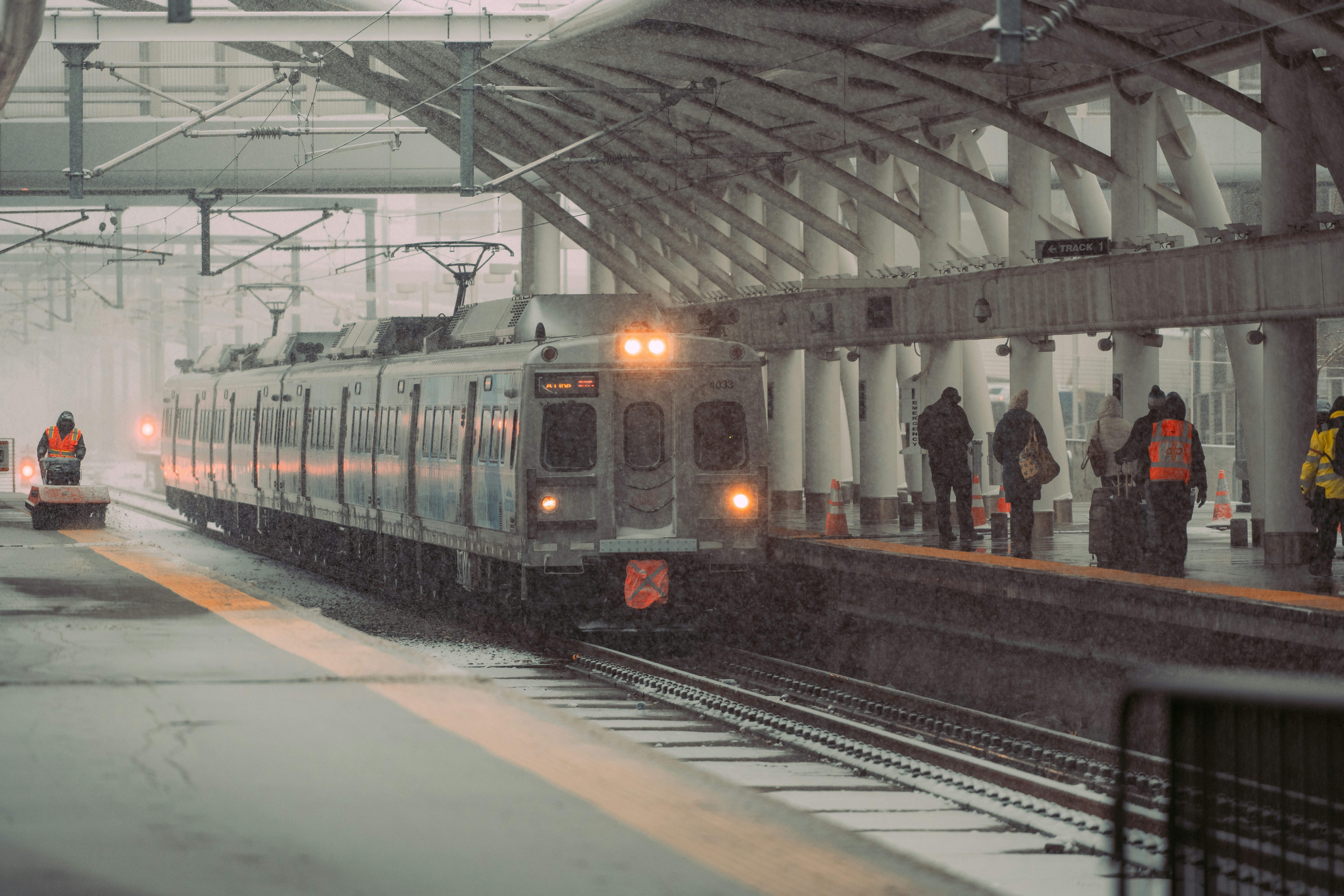 a train pulling into a train station on a snowy day, 