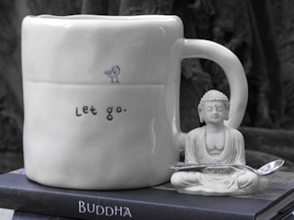 a buddha mug sitting on top of a stack of books