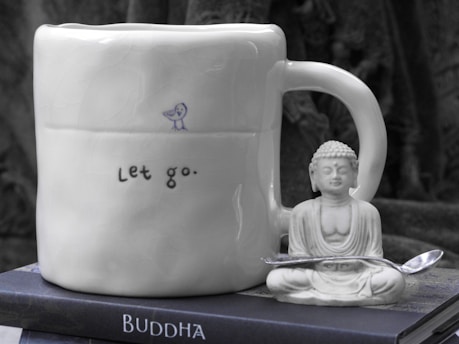 a buddha mug sitting on top of a stack of books