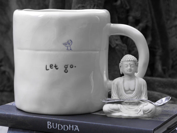 a buddha mug sitting on top of a stack of books