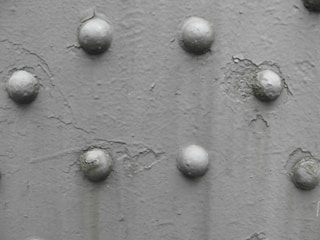 A close-up view of a textured surface with several rounded protrusions arranged in an irregular pattern. The surface appears to have a rough, uneven finish with variations in shading.