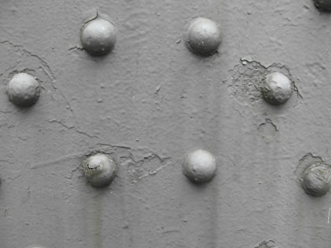 A close-up view of a textured surface with several rounded protrusions arranged in an irregular pattern. The surface appears to have a rough, uneven finish with variations in shading.