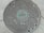 A round manhole cover on a concrete surface featuring a pattern of hexagons. The center of the cover is marked with the word 'Ameritech' in raised letters, surrounded by a slightly greenish patina. The cover has a few visible scratches and wear marks, suggesting it has been in use for some time.