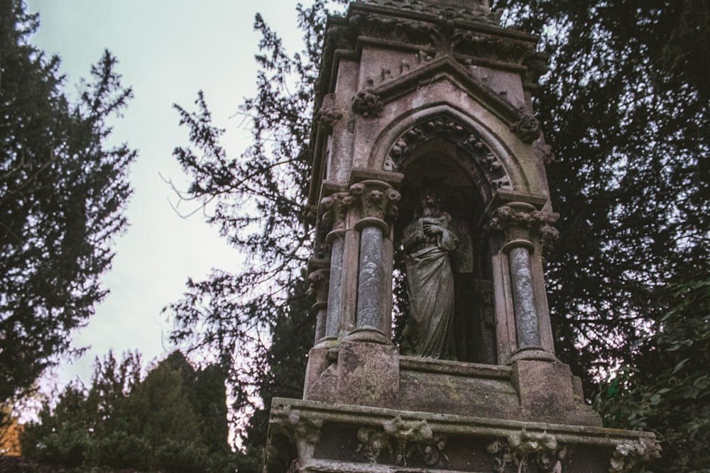 a statue in the middle of a cemetery surrounded by trees