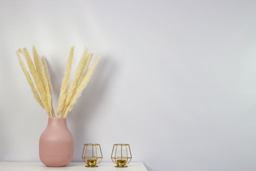 a pink vase sitting on top of a white shelf