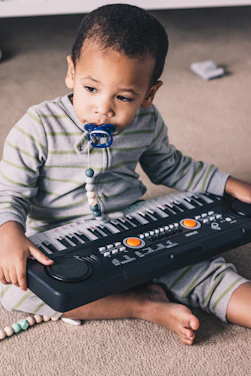 a young boy sitting on the floor with a musical keyboard