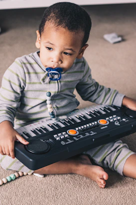 a young boy sitting on the floor with a musical keyboard