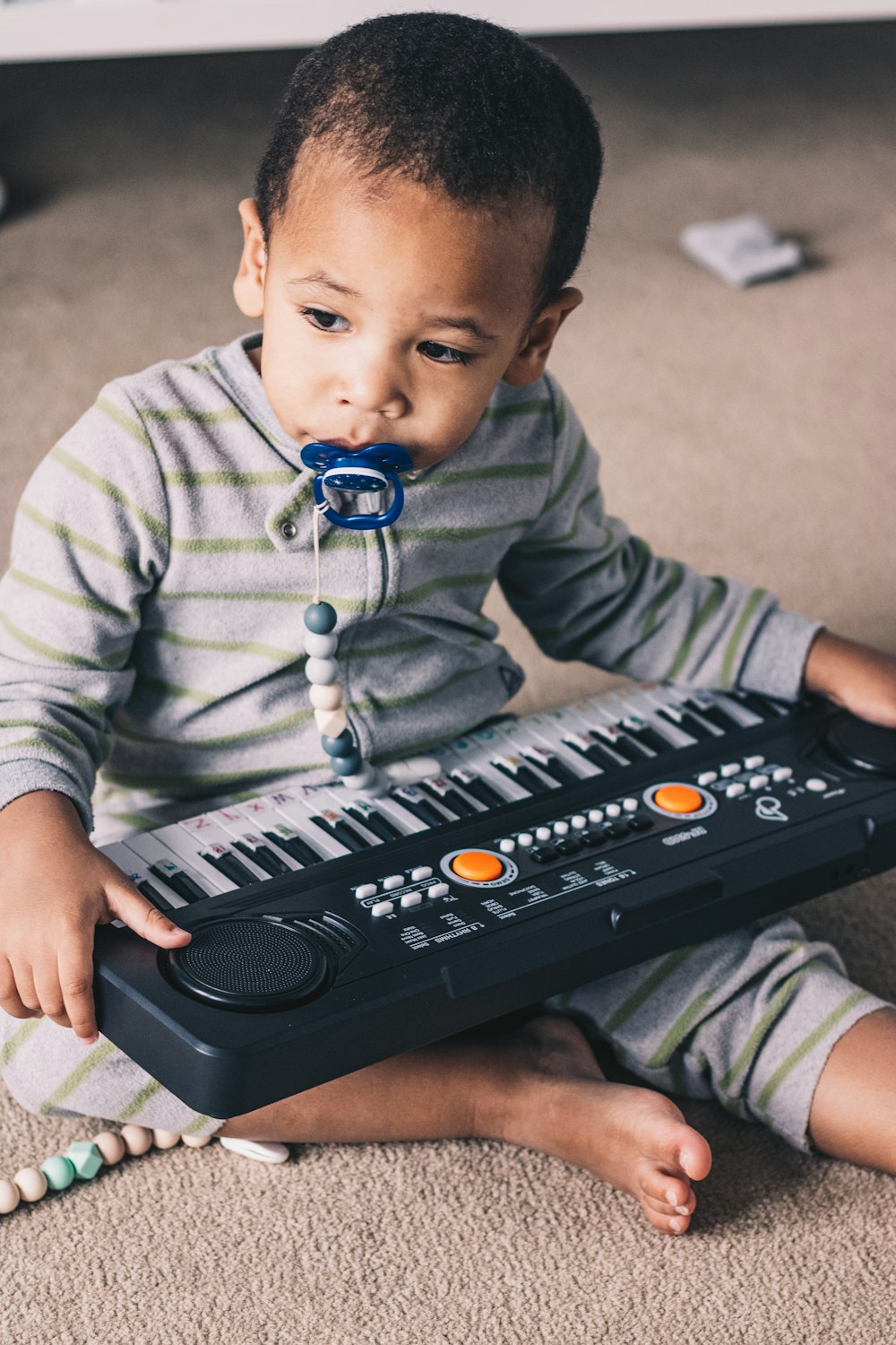 a young boy sitting on the floor with a musical keyboard