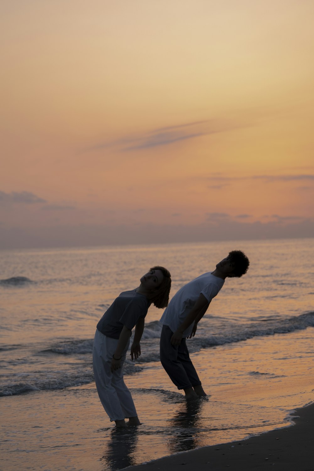 a couple of men standing on top of a beach next to the ocean