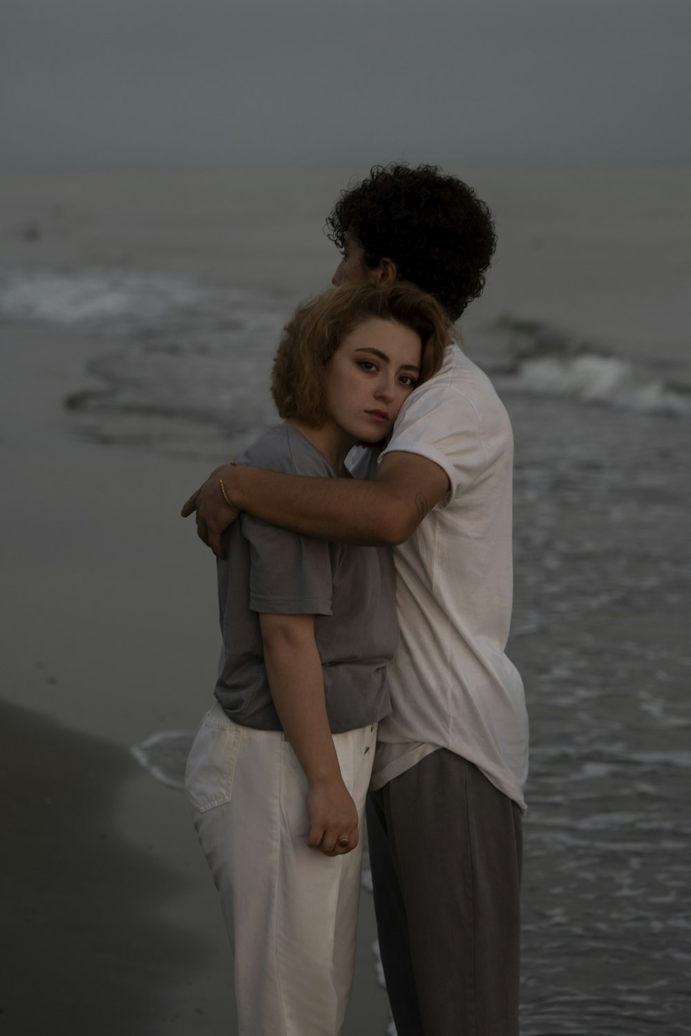 a man and a woman embracing on the beach