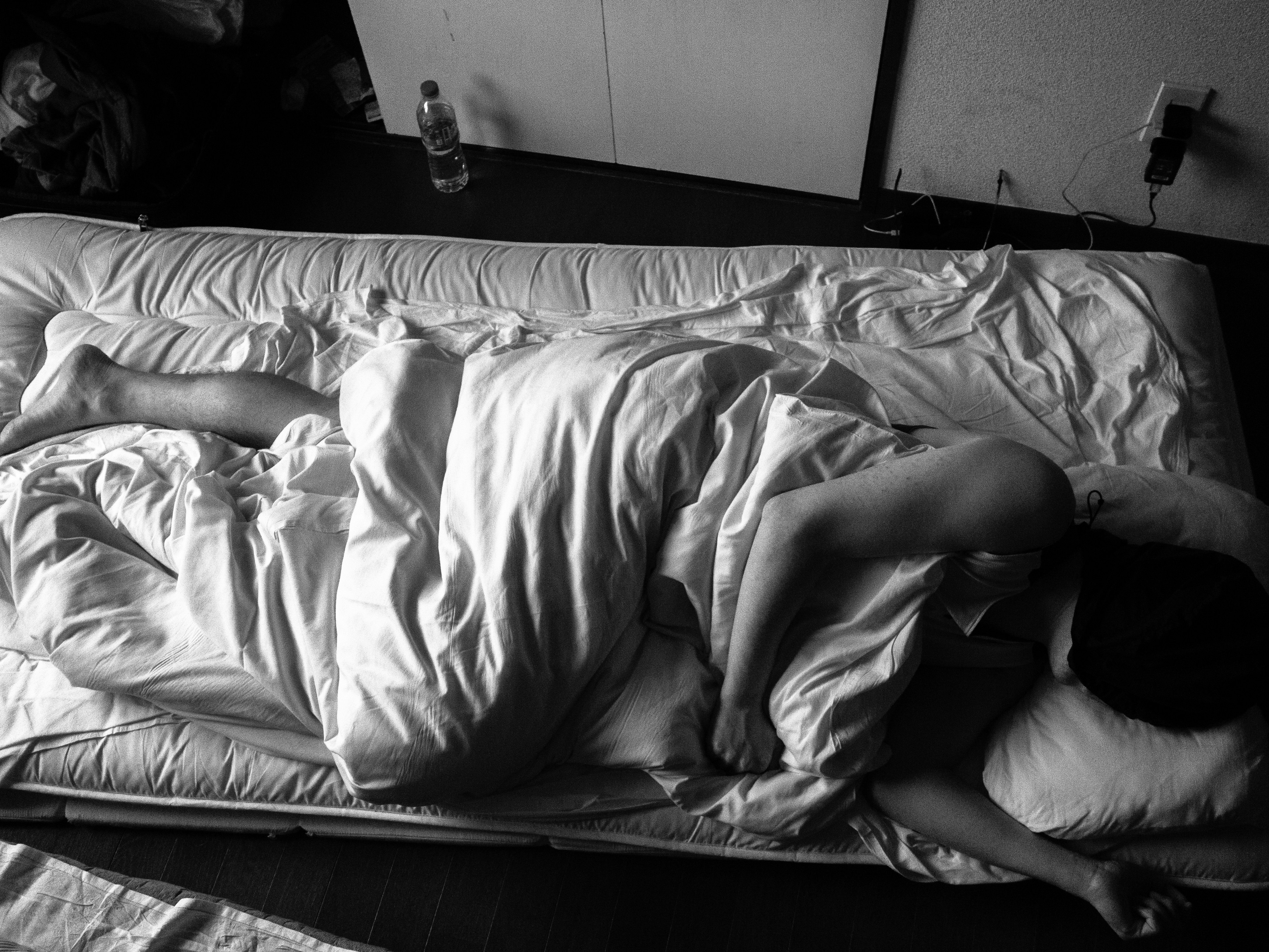 Man sleeping peacefully in dark room, soft moonlight, white bedding, calm atmosphere