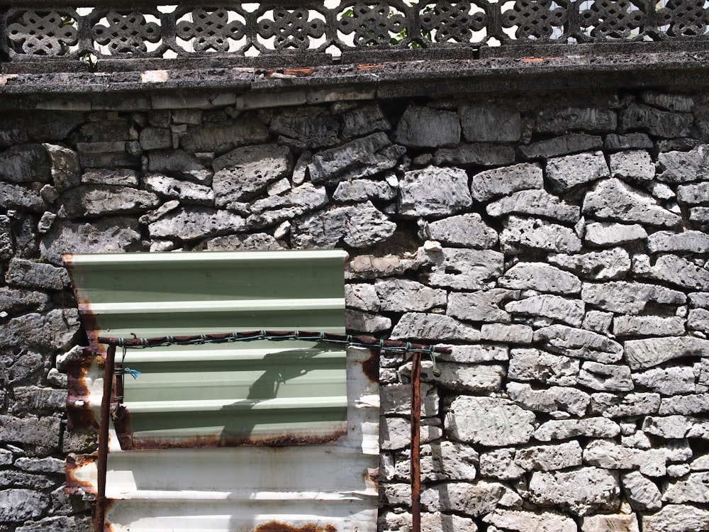 a stone wall with a window and a metal fence