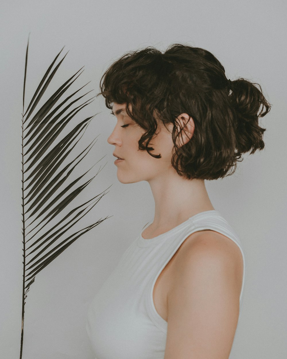 a woman standing in front of a palm leaf