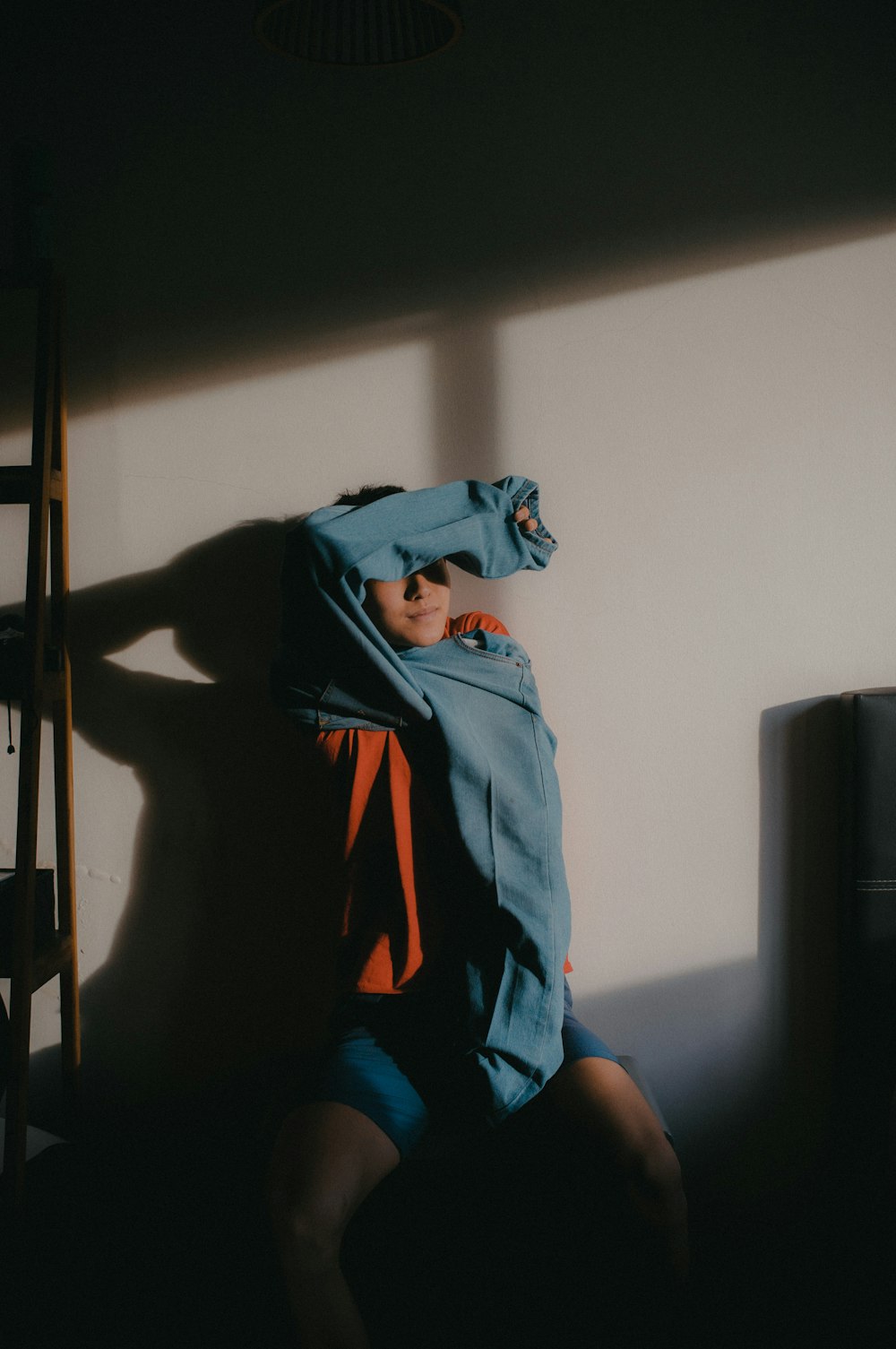 a person sitting in the shadows of a wall