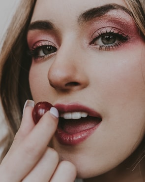 Close-up of a playful makeup look featuring rosy pink eyeshadow and glossy lips.