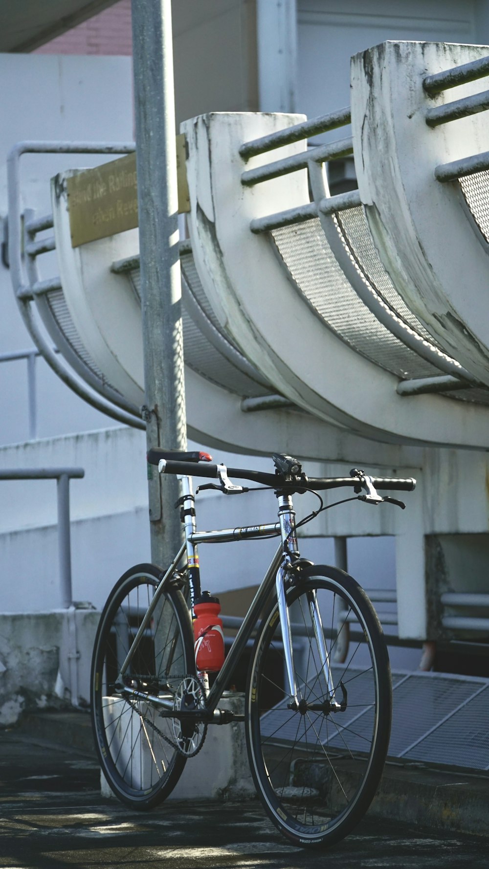 a bike parked next to a pole with a building in the background