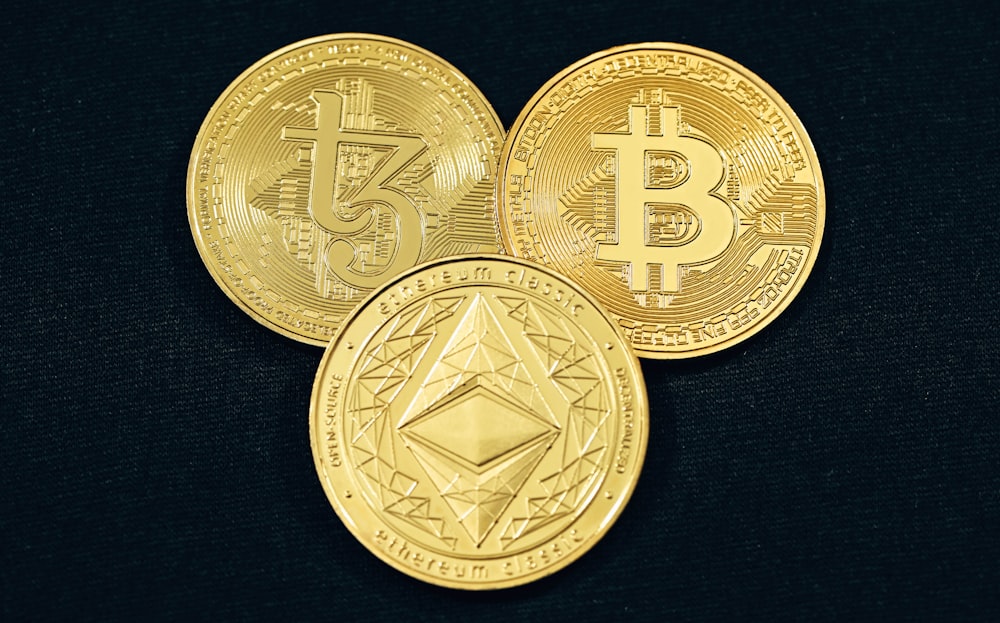 three gold bitcoins on a black background