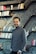 a man standing in front of a bookshelf