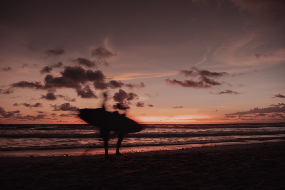 a person standing on a beach holding a surfboard